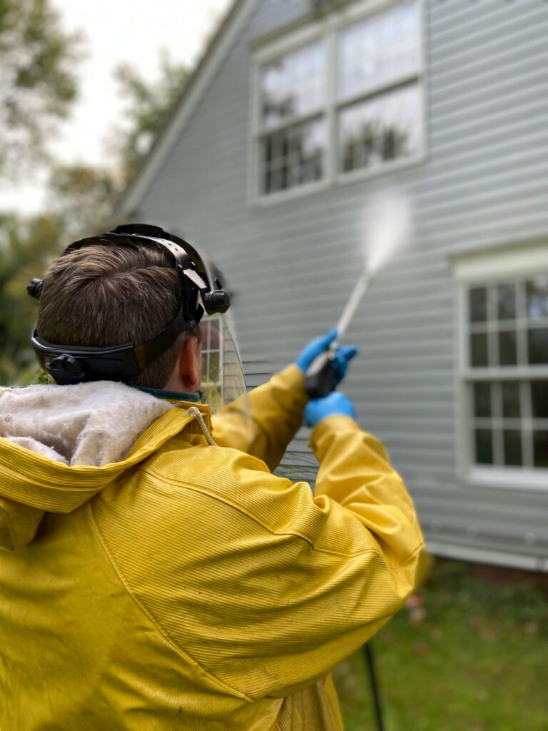 worker pressure washer the exterior siding of a residential home with a high - pressure wand