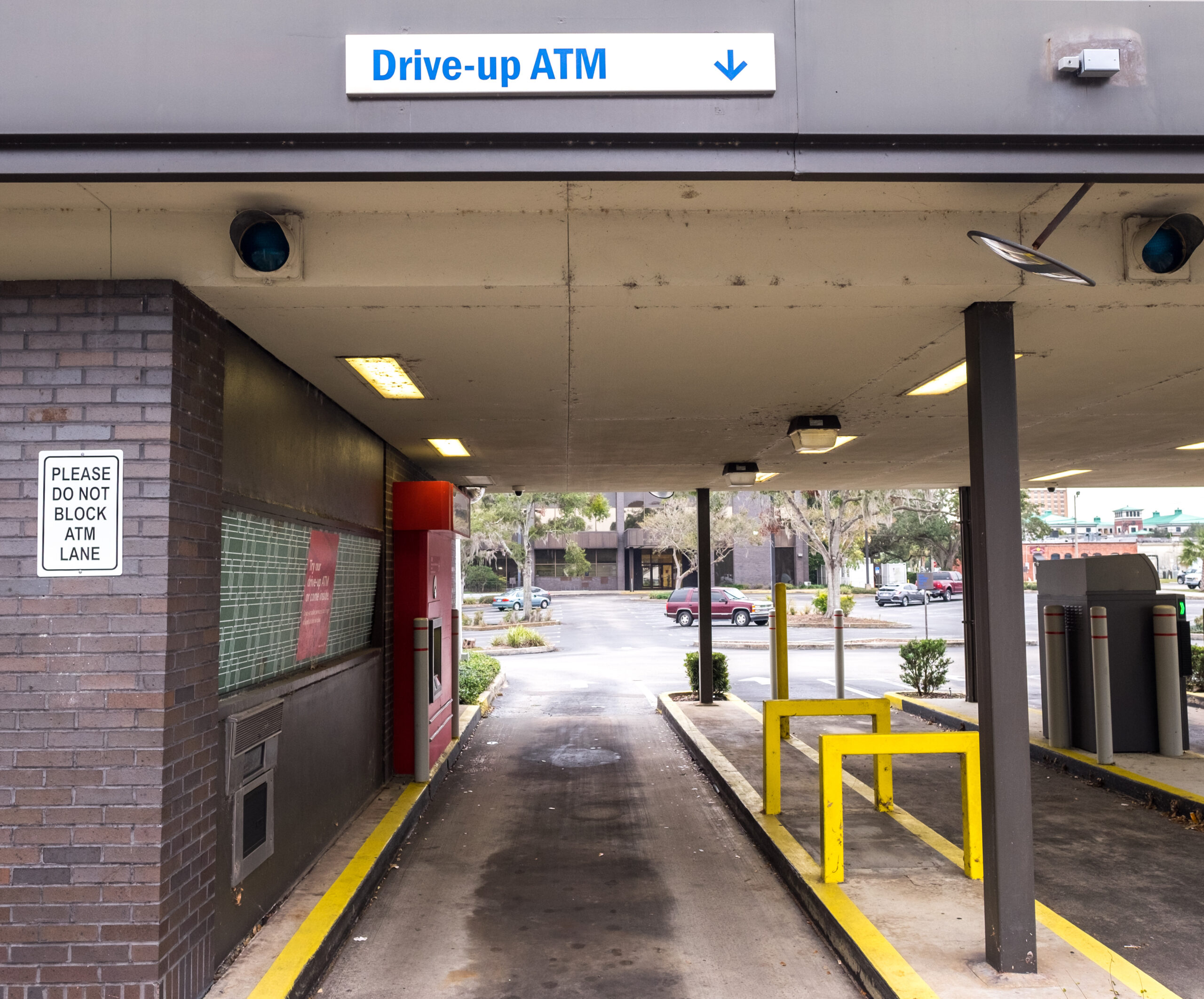 drive thru ATM lane with lanes, bollards, and overhead structure prepared for commercial pressure washing in Sacramento, Ca